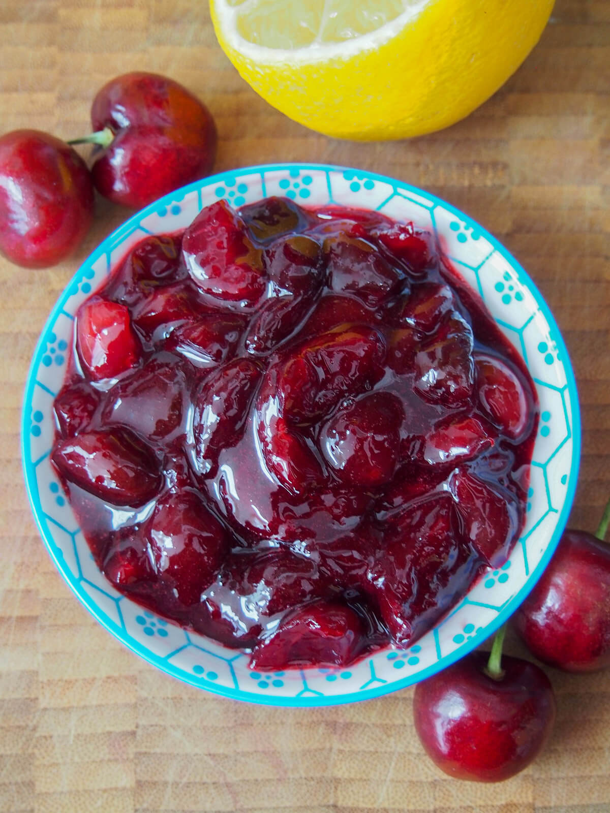 small dish with cherry compote and cherries to side and lemon above