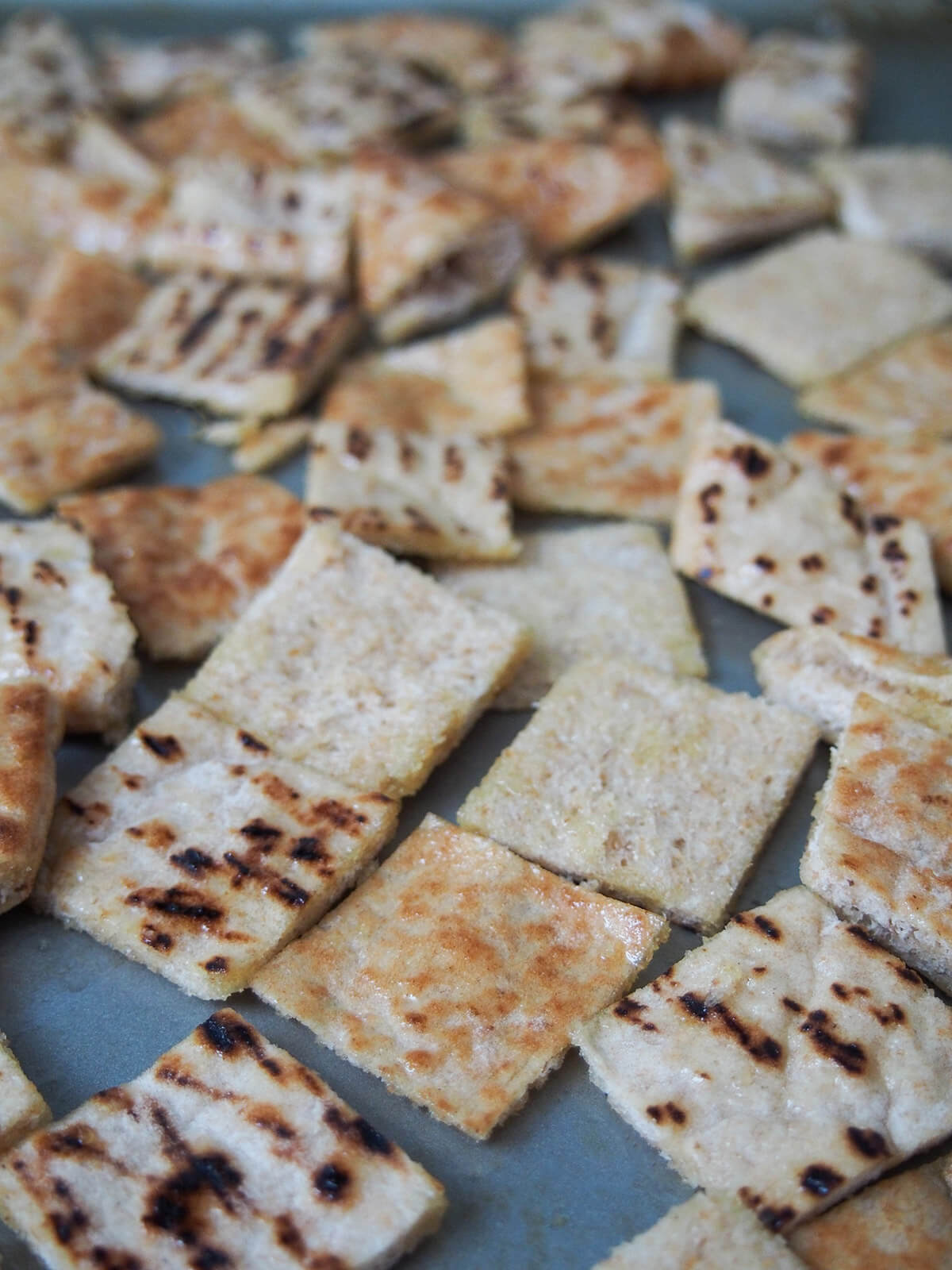 squares of pit bread coated with olive oil on baking sheet