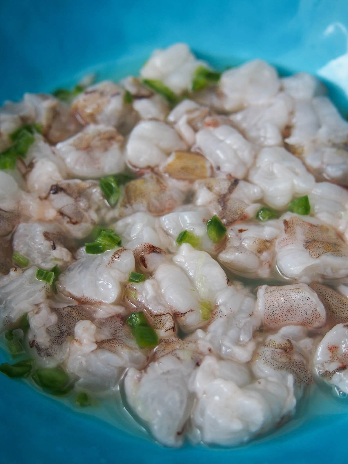 chopped shrimp in bowl with lime juice and chili pieces