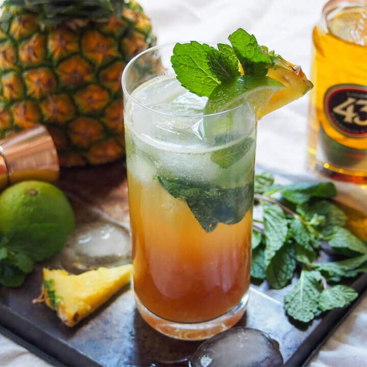 glass of 43 pineapple mojito garnished with mint, lime and pineapple slice