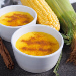 dish of Brazilian corn pudding with another and corn cob behind