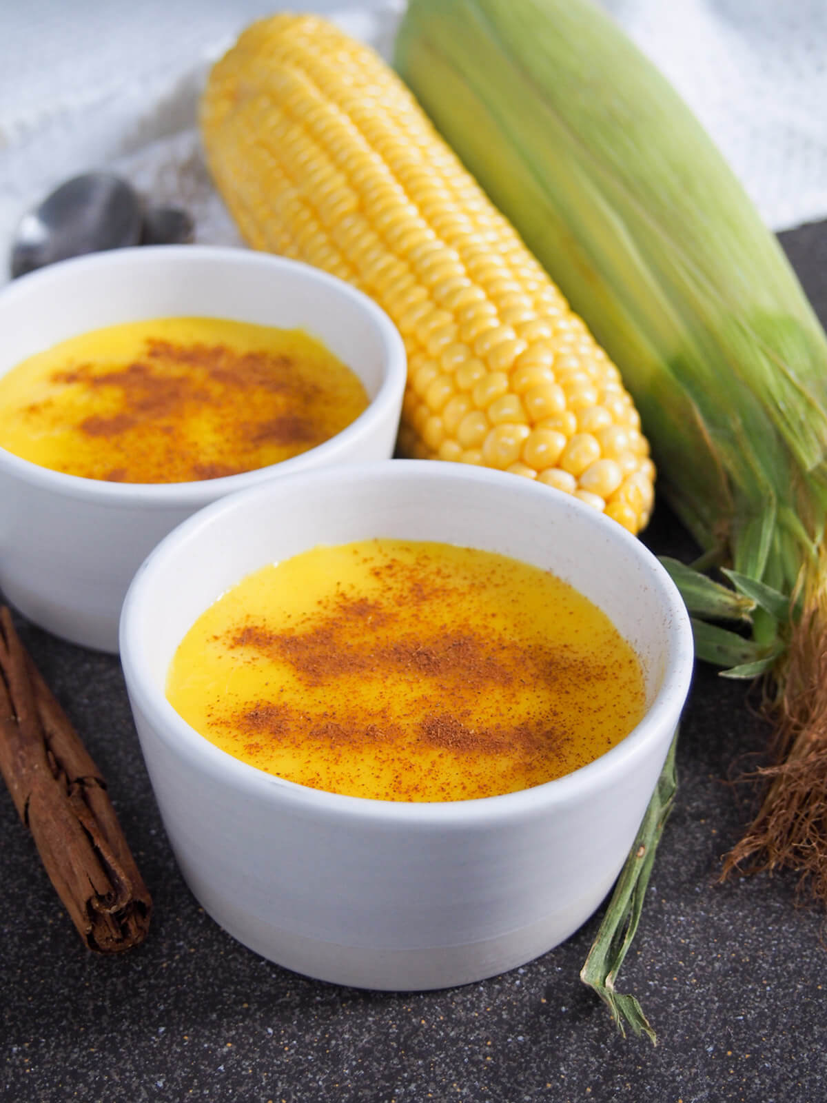 dishes of Brazilian corn pudding with two cobs of corn behind
