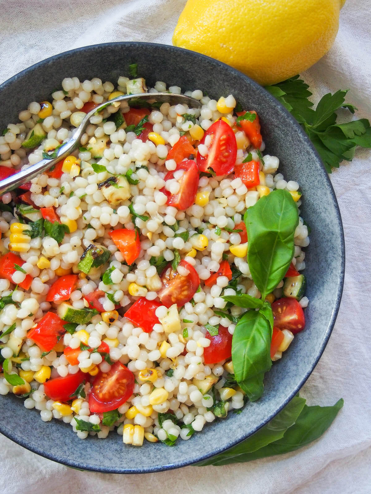 Israeli couscous salad with grilled vegetables with lemon above bowl