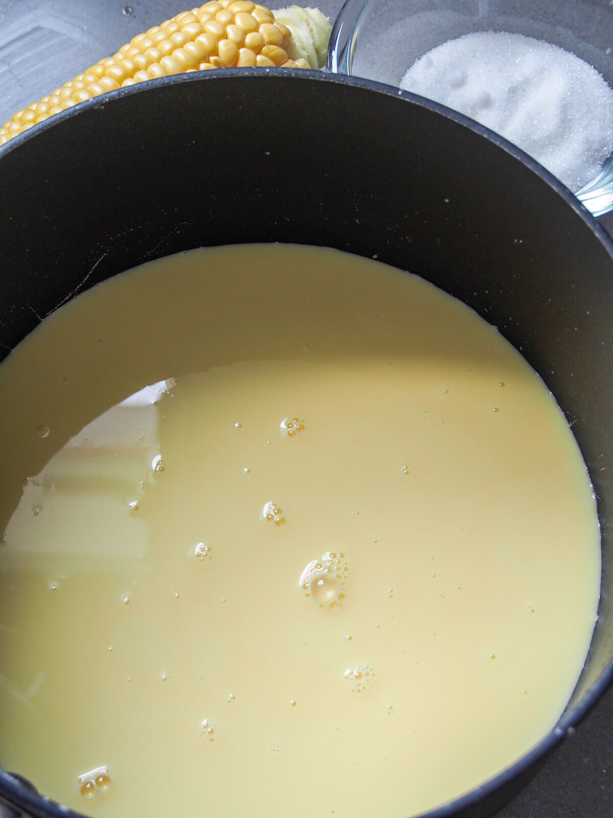 corn milk in pot with sugar behind