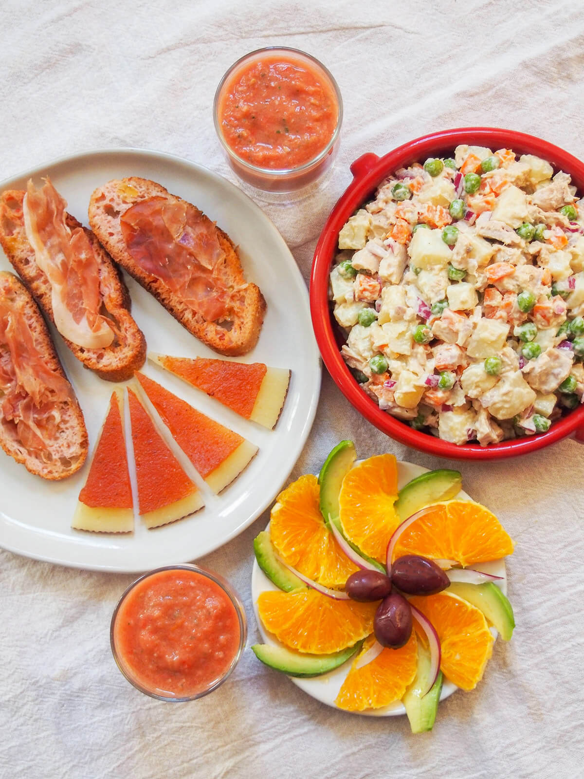 plates with easy Spanish cold tapas salad, pan con tomate, potato salad and glasses with gazpacho