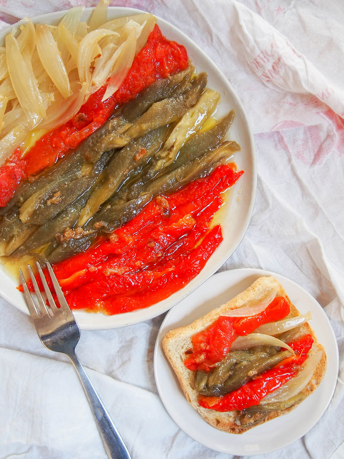 plate of escalivada Catalan roast vegetables with fork on it and some of vegetables on bread