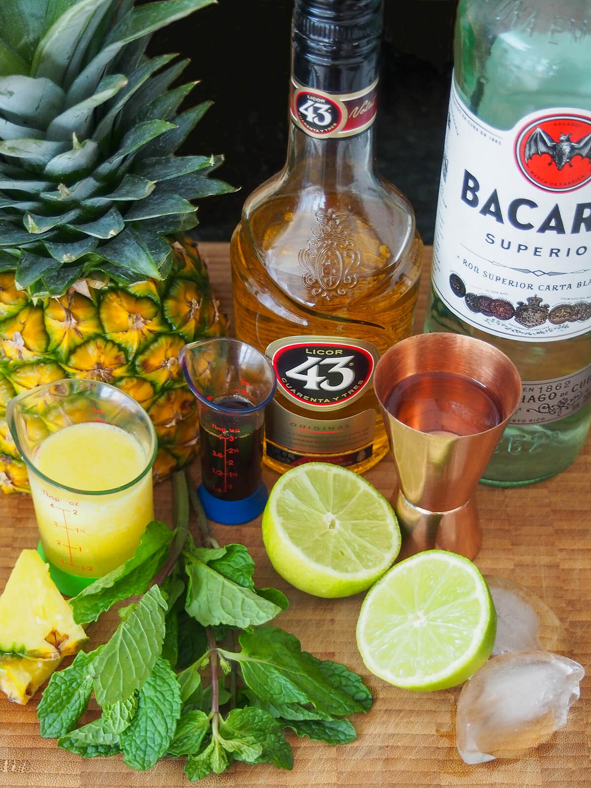 pineapple, bottles of licor 43 and rum with lime, mint and measures in front