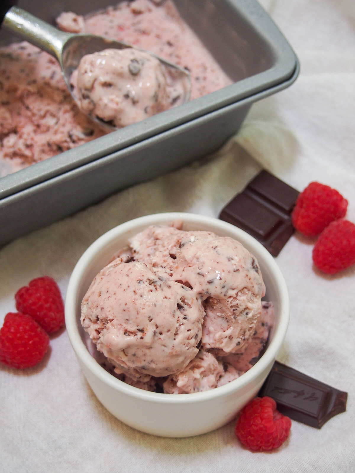dish with no churn raspberry chocolate chip ice cream and scoop in container behind