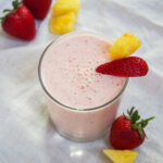 glass of strawberry pineapple smoothie garnished with fruit