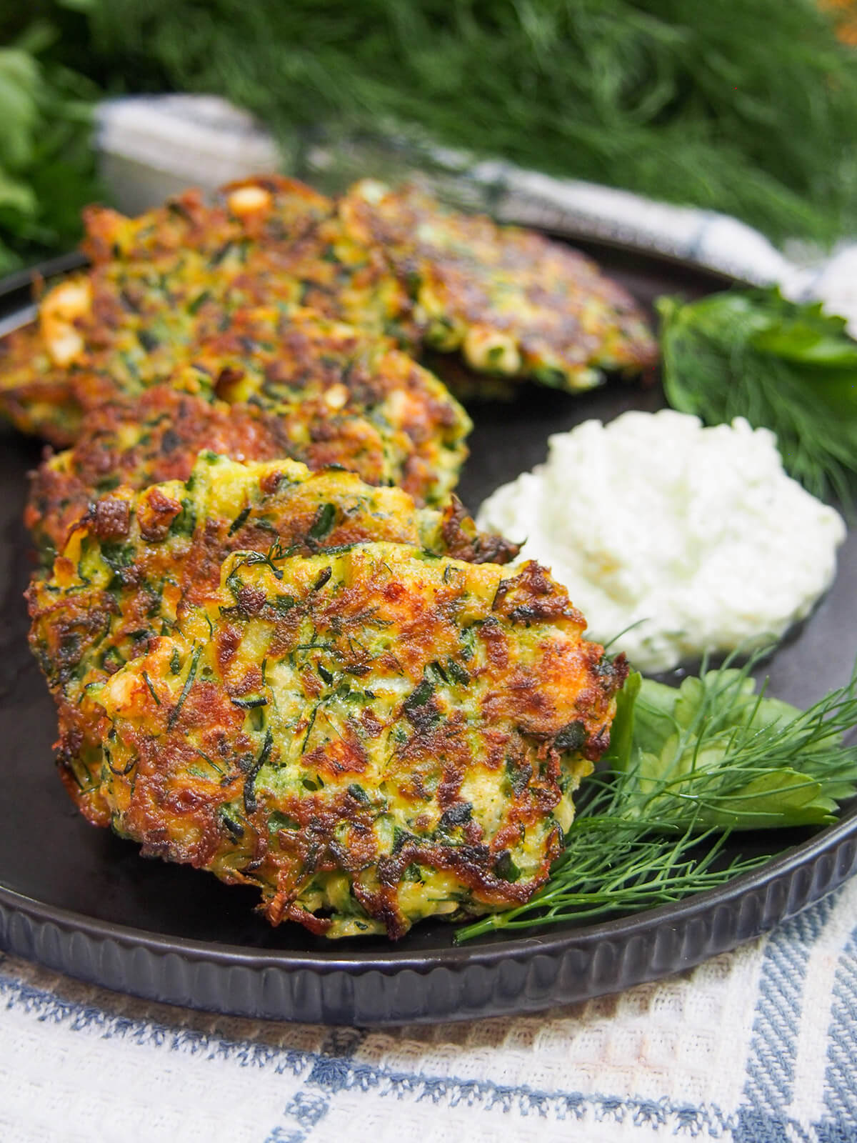 row of Greek zucchini fritters resting against other with sauce to side