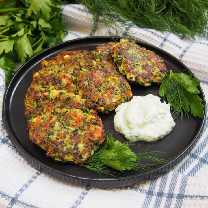 plate of Greek zucchini fritters with some sauce to side of plate