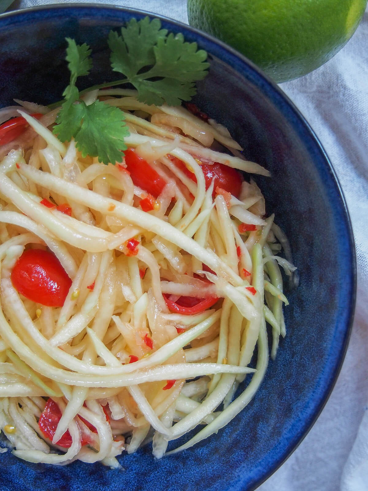 close overhead view of Lao green papaya salad in blue bowl