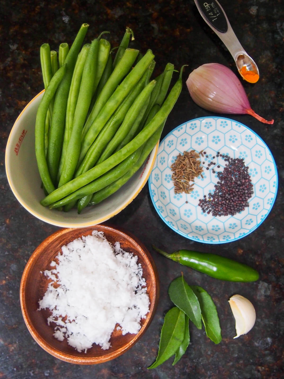 bowls with beans, coconut, mustard and cumin seeds with shallot, curry leaves and chili to side