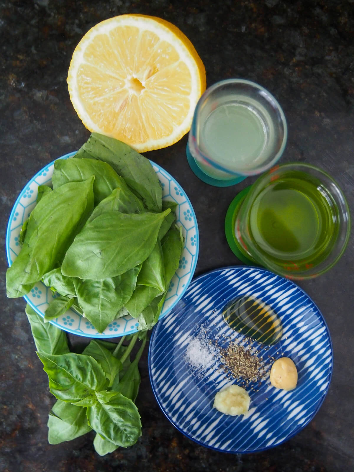 plates with basil leaves, salt, pepper, mustard and garlic plus measures with lemon and oli