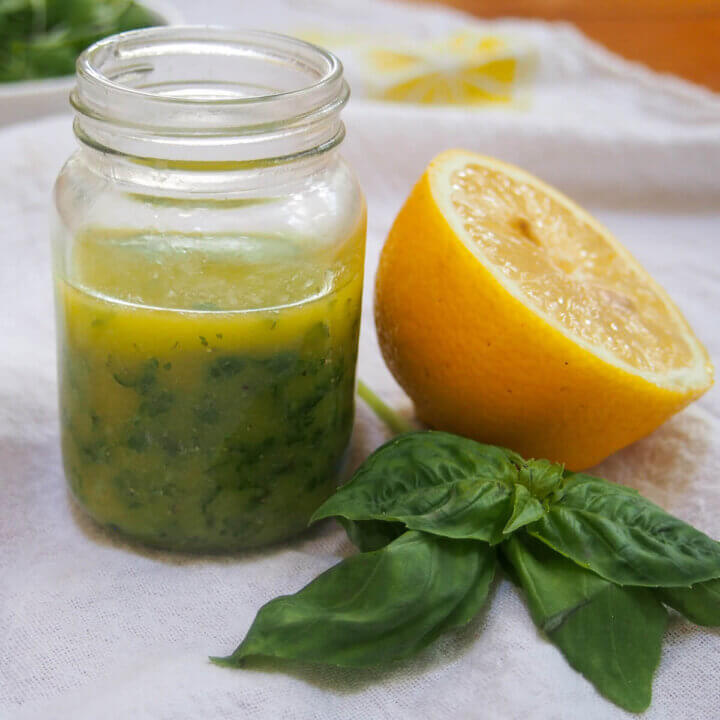 jar of lemon basil vinaigrette with lemon and sprig of basil to side
