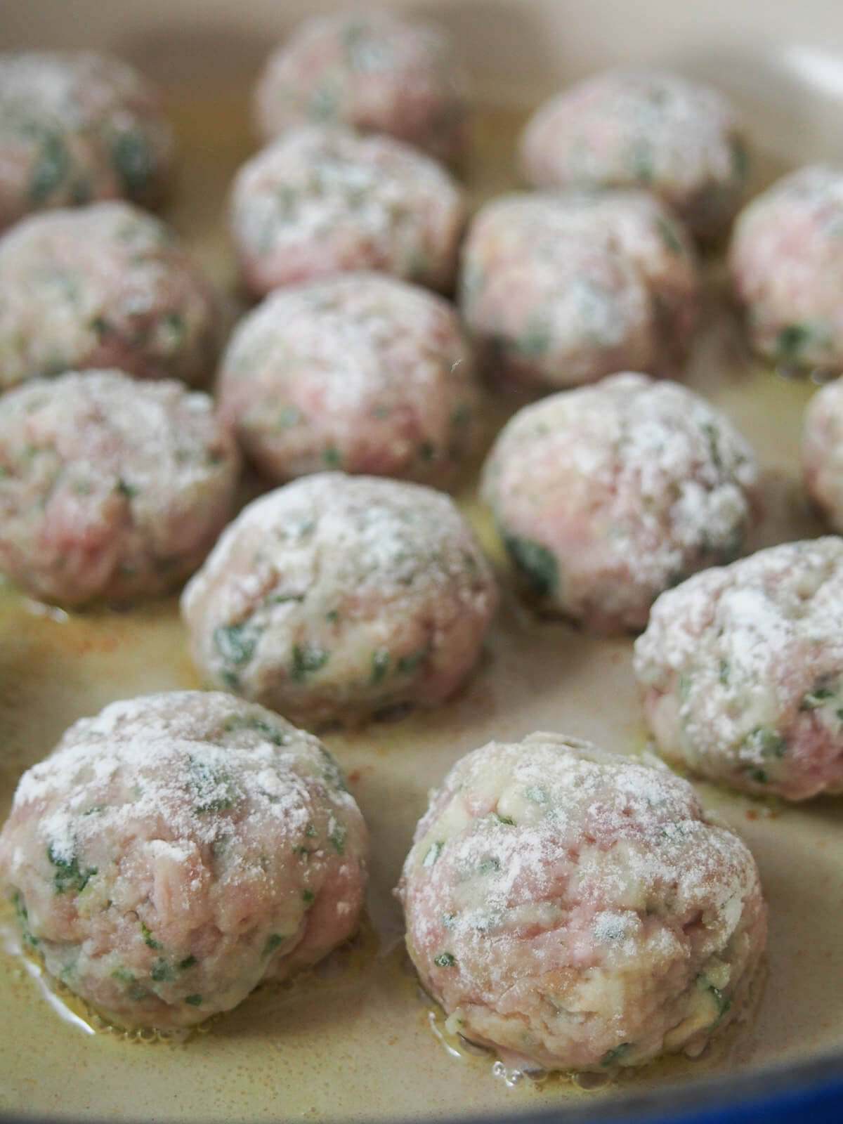 floured meatballs starting to cook in pan