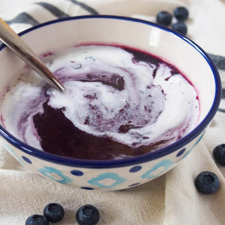 a bowl of Swedish blueberry soup topped with cream