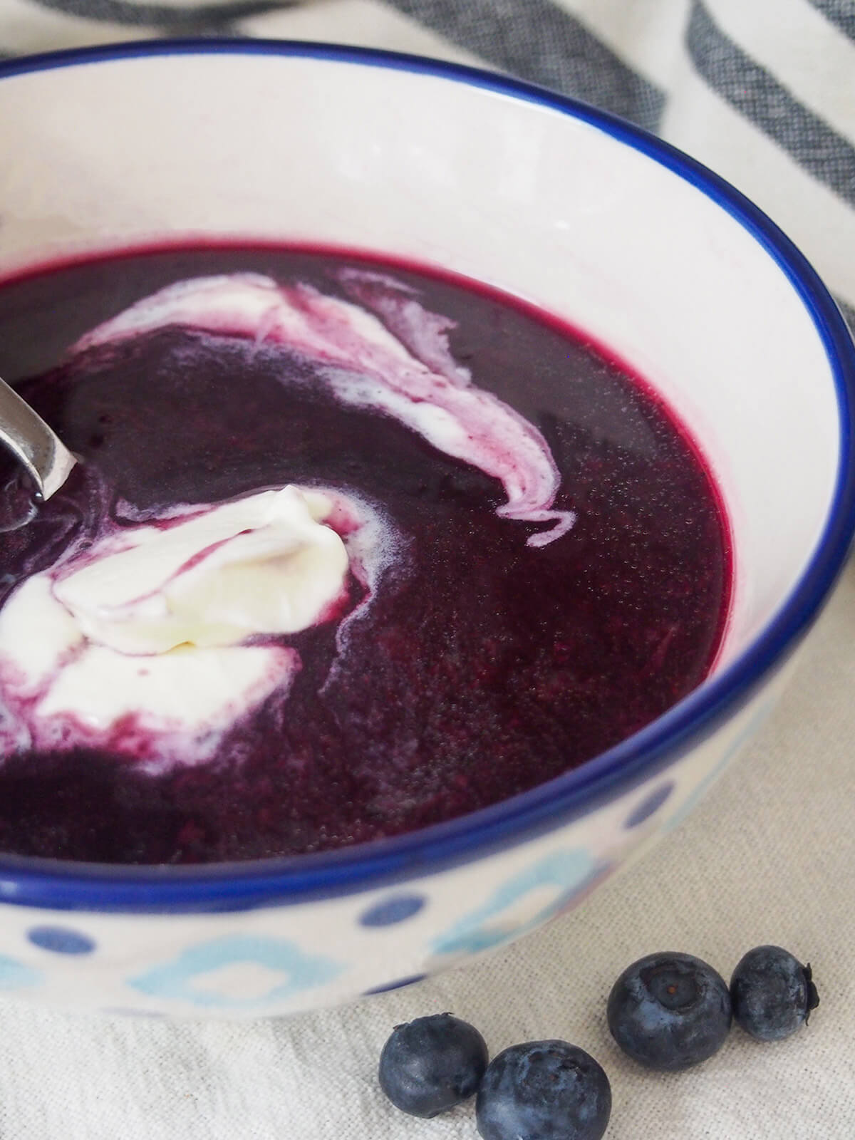 side view of bowl of Swedish blueberry soup with cream on top