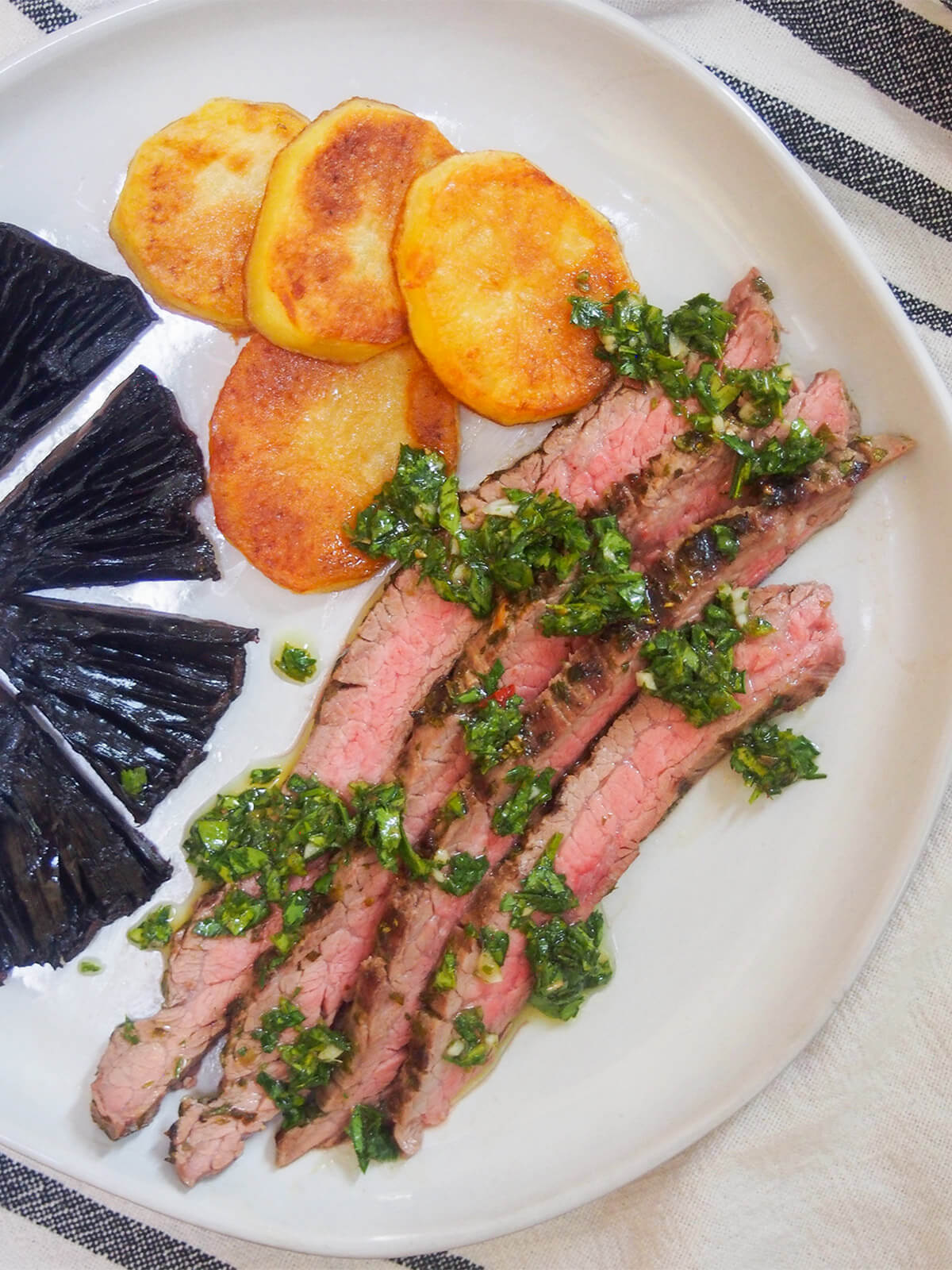 This chimichurri marinated steak is easy to make, tender and packed with delicious herb, garlic flavor. Perfect for an easy, flavorful meal, and a great way to make the most of a cheaper cut. chimichurri marinated steak and potatoes on plate from overhead