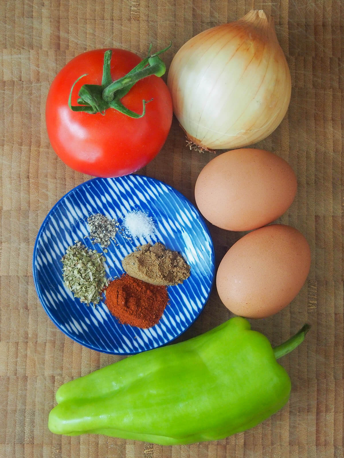 tomato, onion, pepper, eggs and small plate with spices