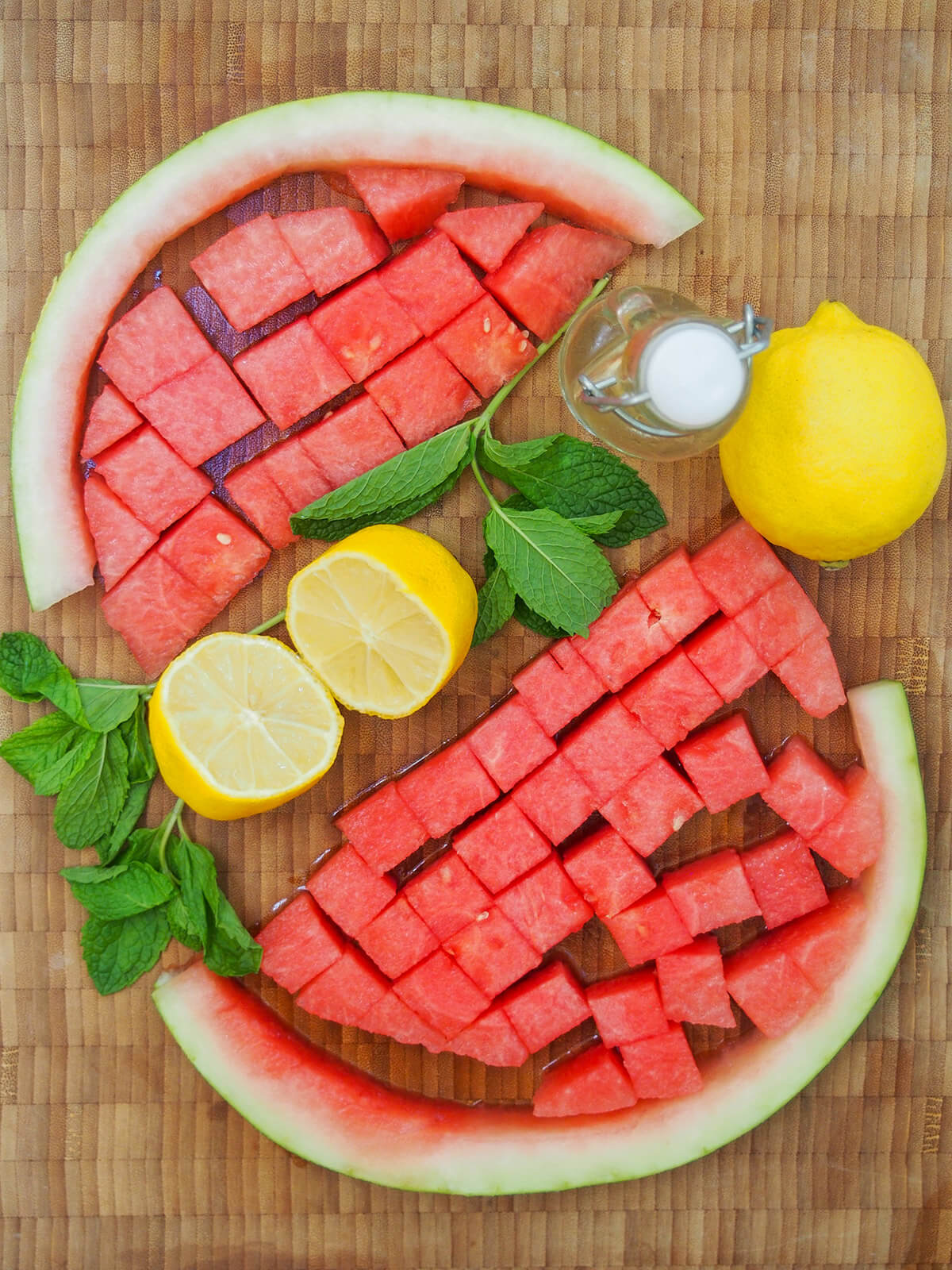 chunks of watermelon, lemons and mint sprigs on chopping board