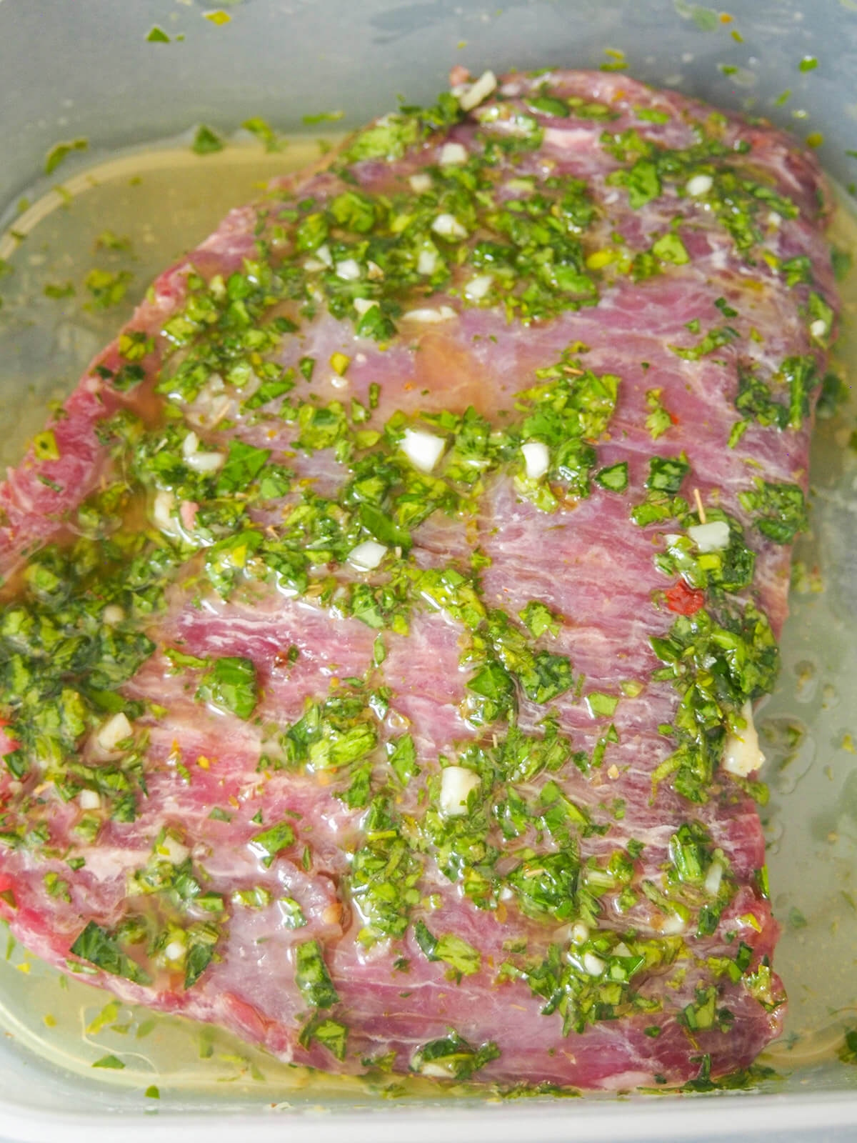 steak marinating in chimichurri steak in box with chimichurri marinade