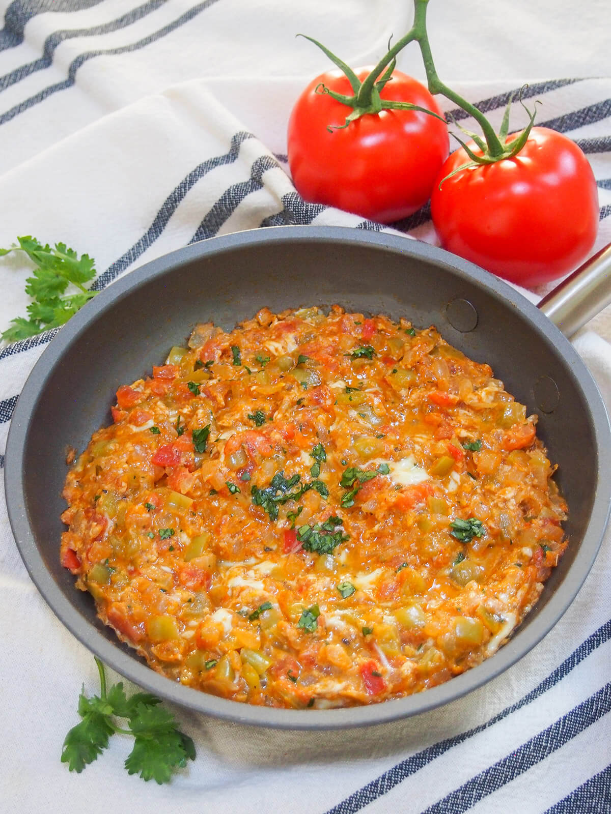 skillet of menemen Turkish scrambled eggs with tomatoes behind