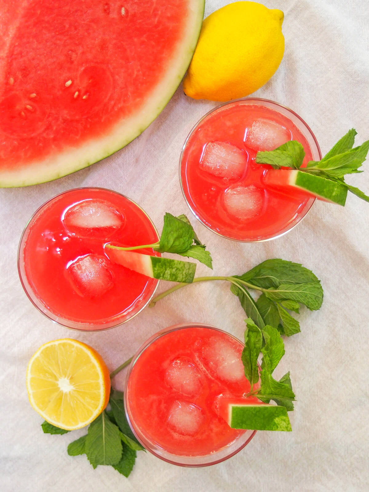 glasses of watermelon lemonade from overhead with chunk of watermelon and lemon above