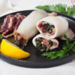 close view of cut Sicilian style stuffed squid with whole one behind