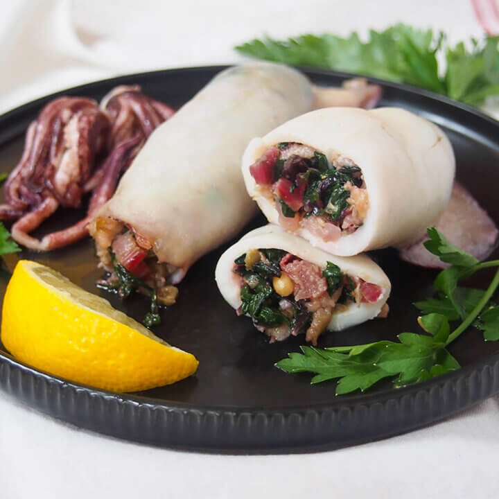 close view of cut Sicilian style stuffed squid with whole one behind