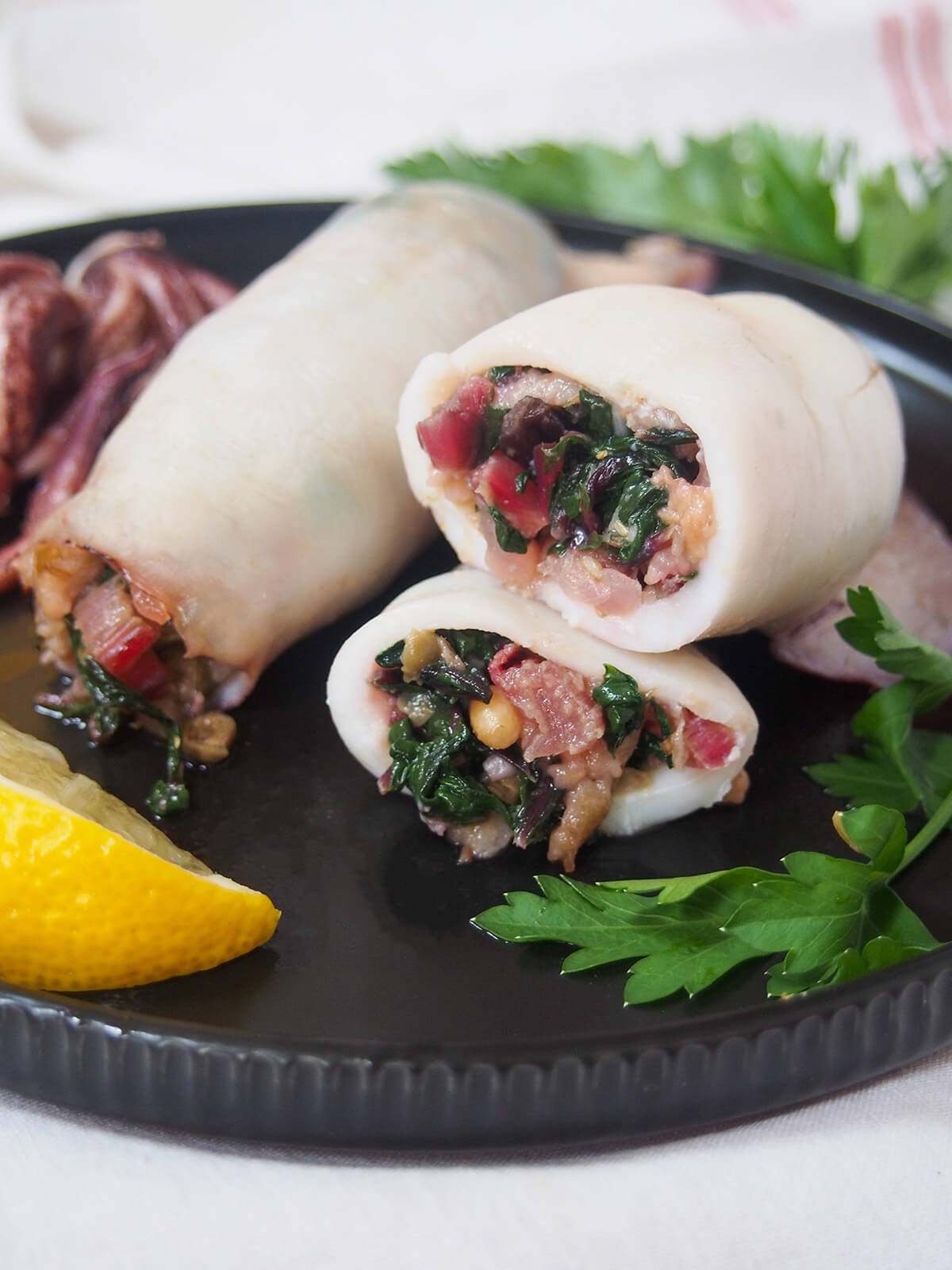 cut Sicilian style stuffed squid stacked on each other with whole one behind