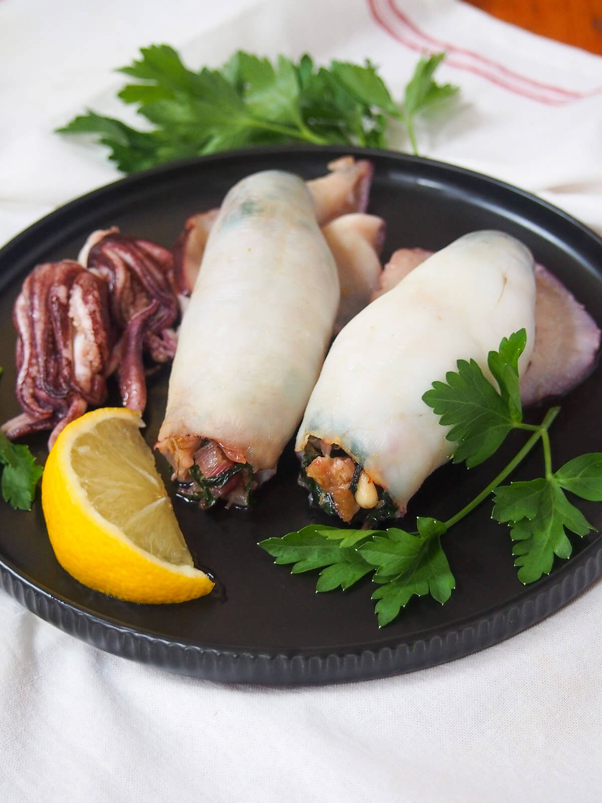 overhead view of two Sicilian style stuffed squid on black plate