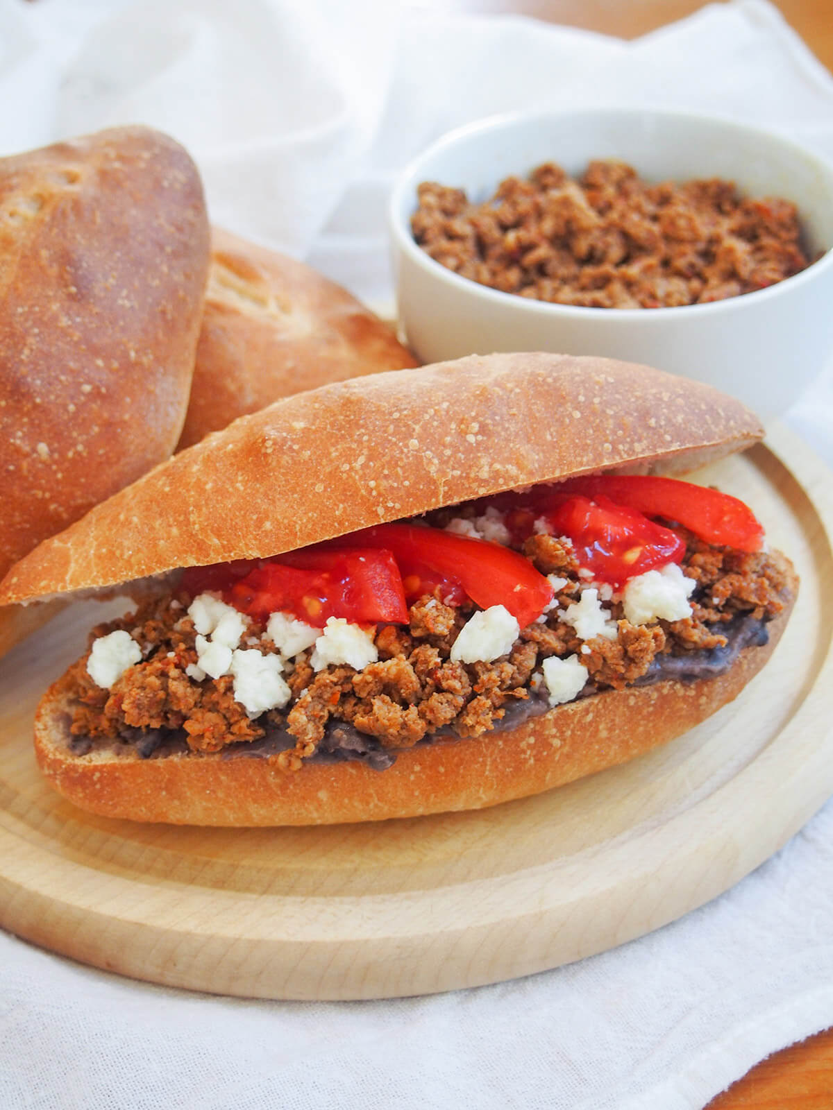 chorizo torta with bowl of chorizo and bolillo rolls behind