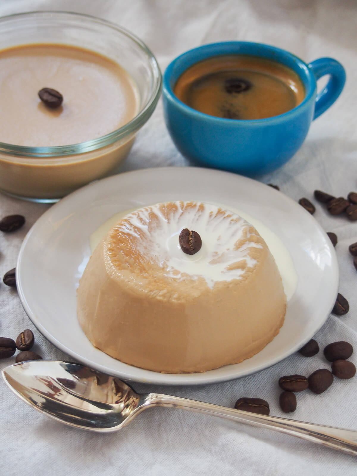 coffee panna cotta on plate topped with cream with spoon in front