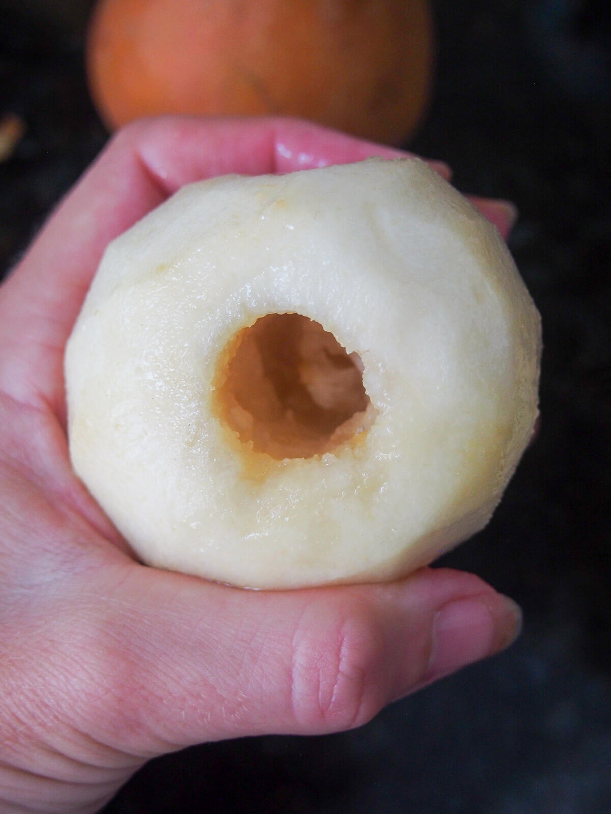 holding a pear in hand with hollow in core removed from bottom of pear