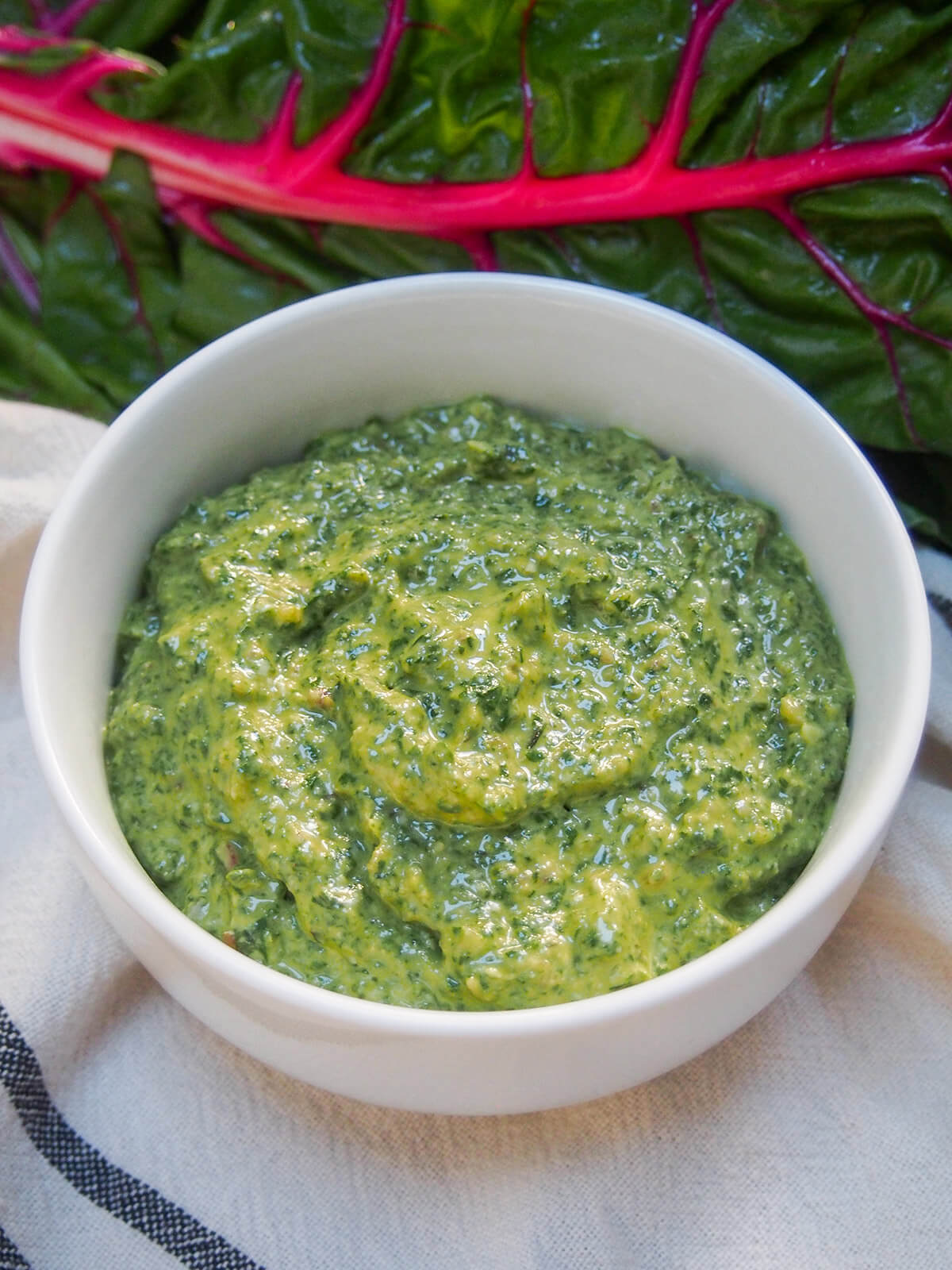 bowl of creamy chard pesto with chard leaf behind