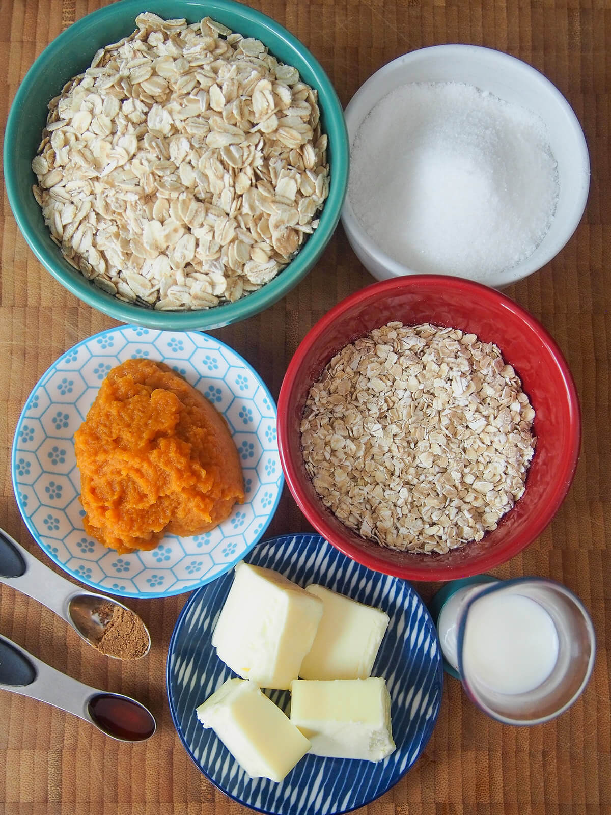 bowls of oats, sugar, pumpkin, milk and plate with butter,