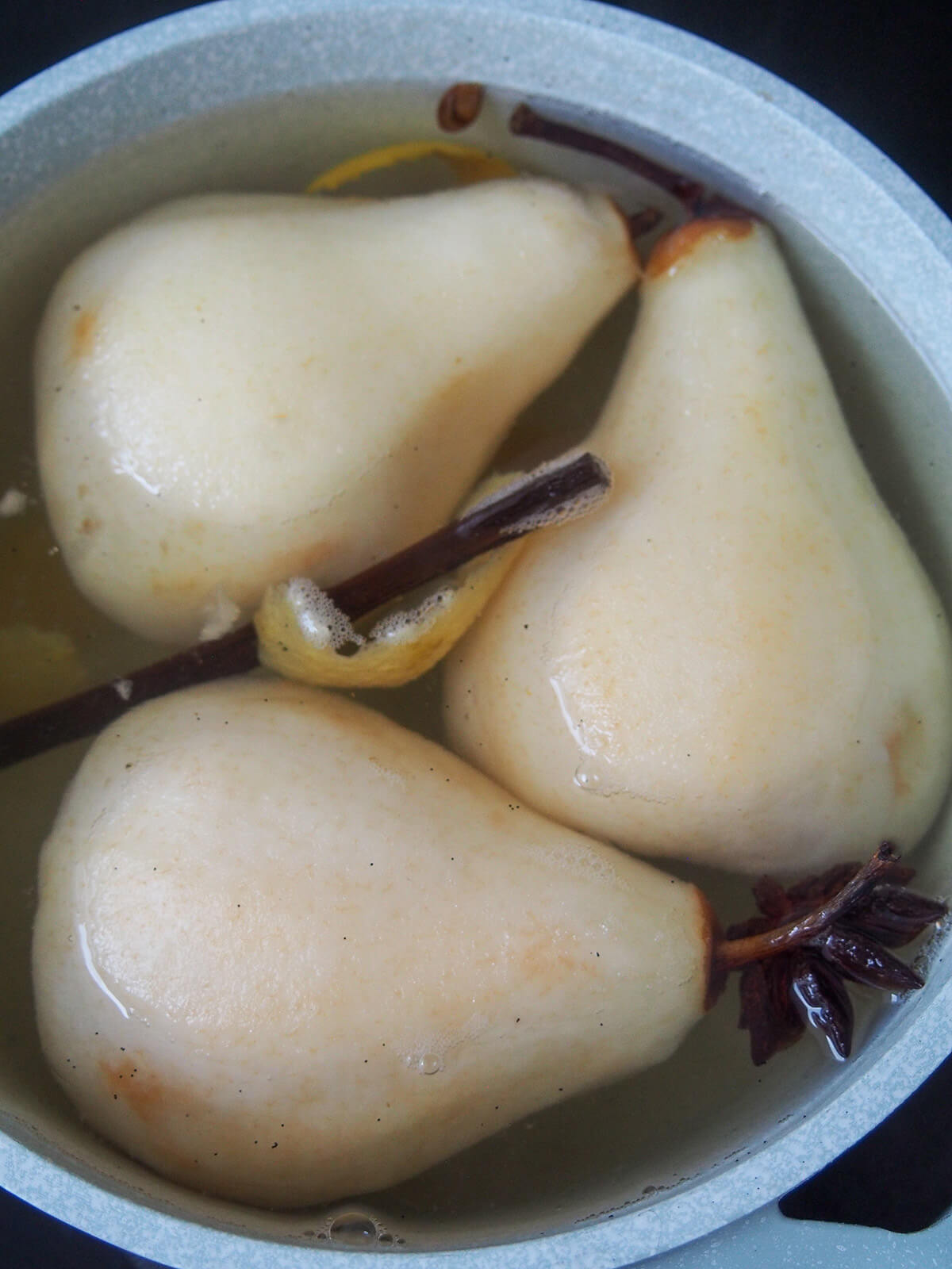 pears in a pot with poaching liquid, vanilla pod and star anise