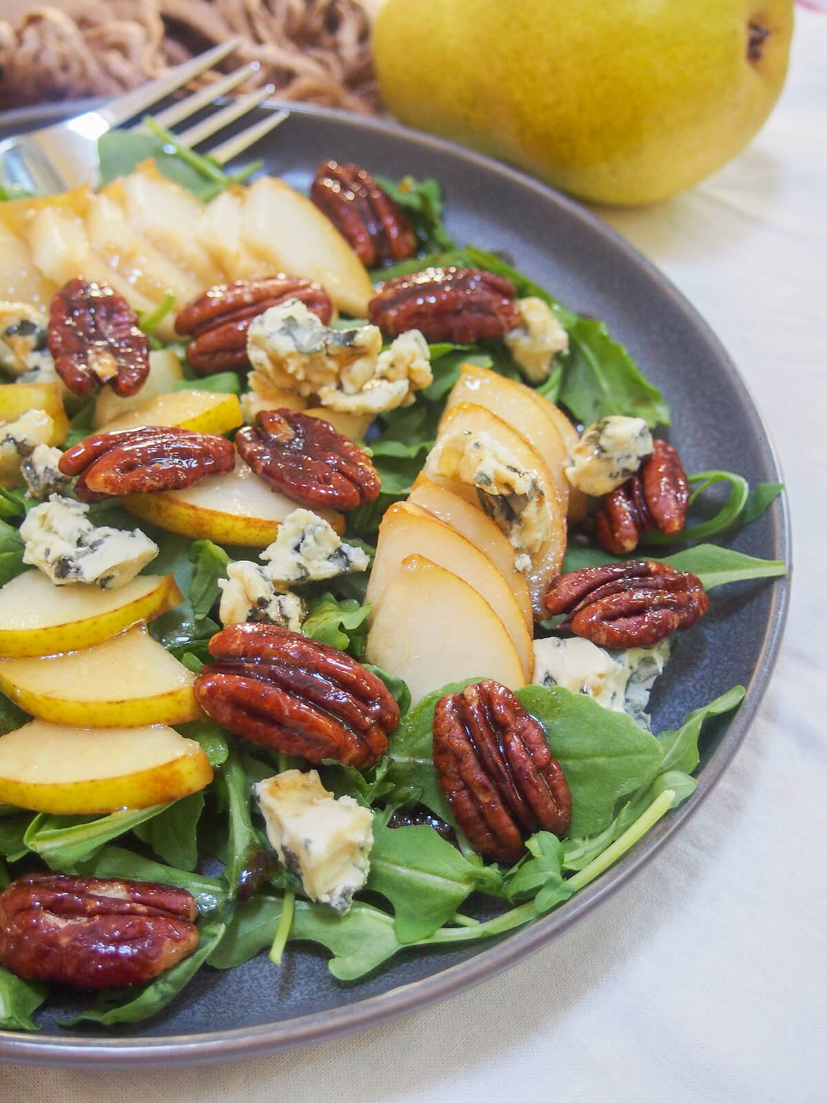 This pear gorgonzola salad is so easy to make and has a great mix of flavors. Plus don't skip the maple candied pecans that add a delicious crunch and sweetness. Great as a side, a light appetizer, or enjoy a bigger serving as a lunch. side view of a plate of pear gorgonzola salad