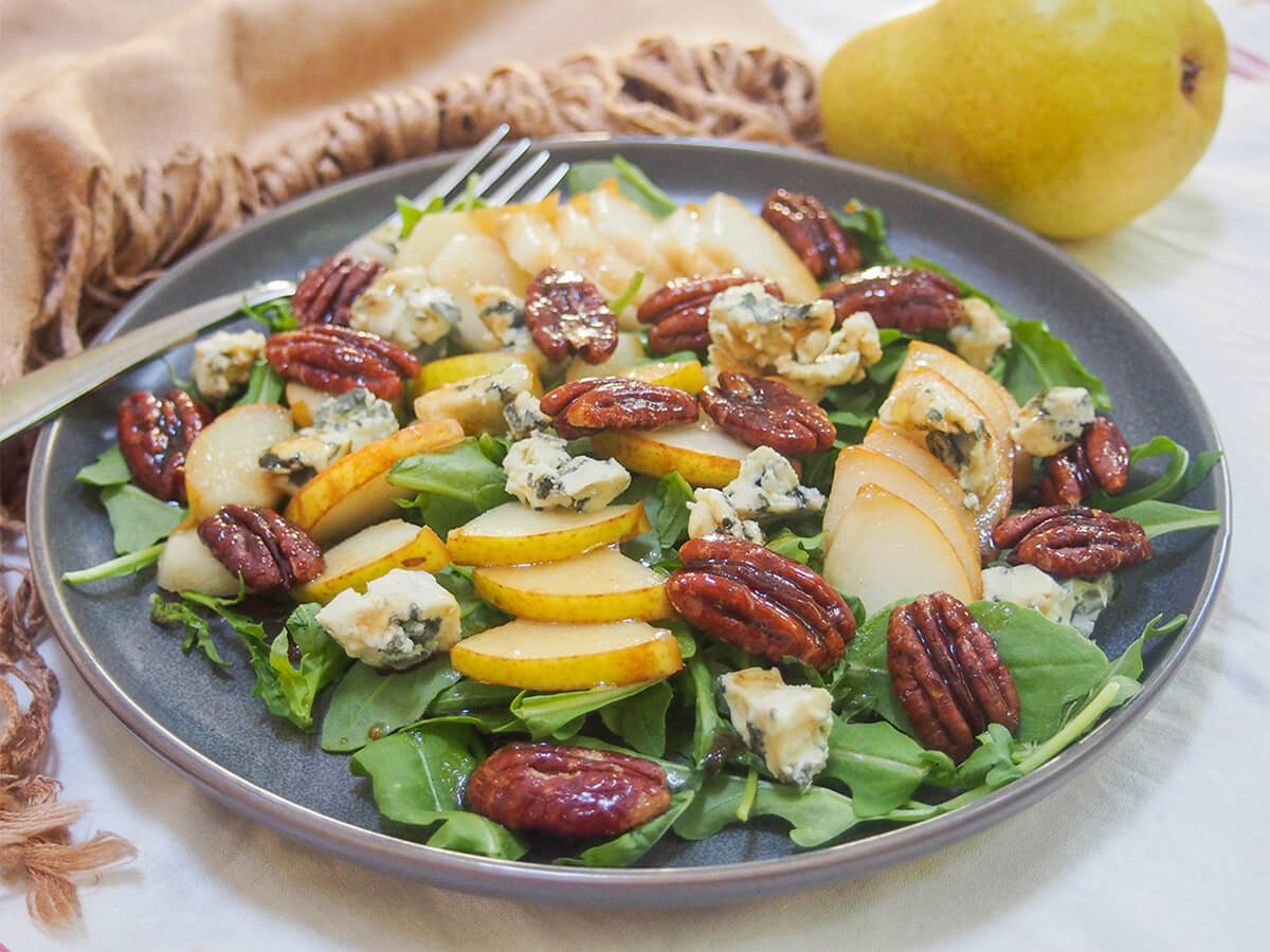 This pear gorgonzola salad is easy to make and has great flavors. Plus don't miss the healthier candied pecans. It makes a delicious side salad or make a big old bowl for lunch. plate of pear gorgonzola salad with fork to back of plate