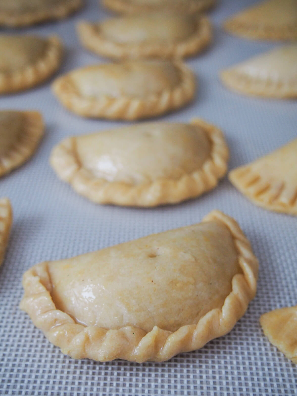 formed pumpkin empanadas on baking sheet before baking