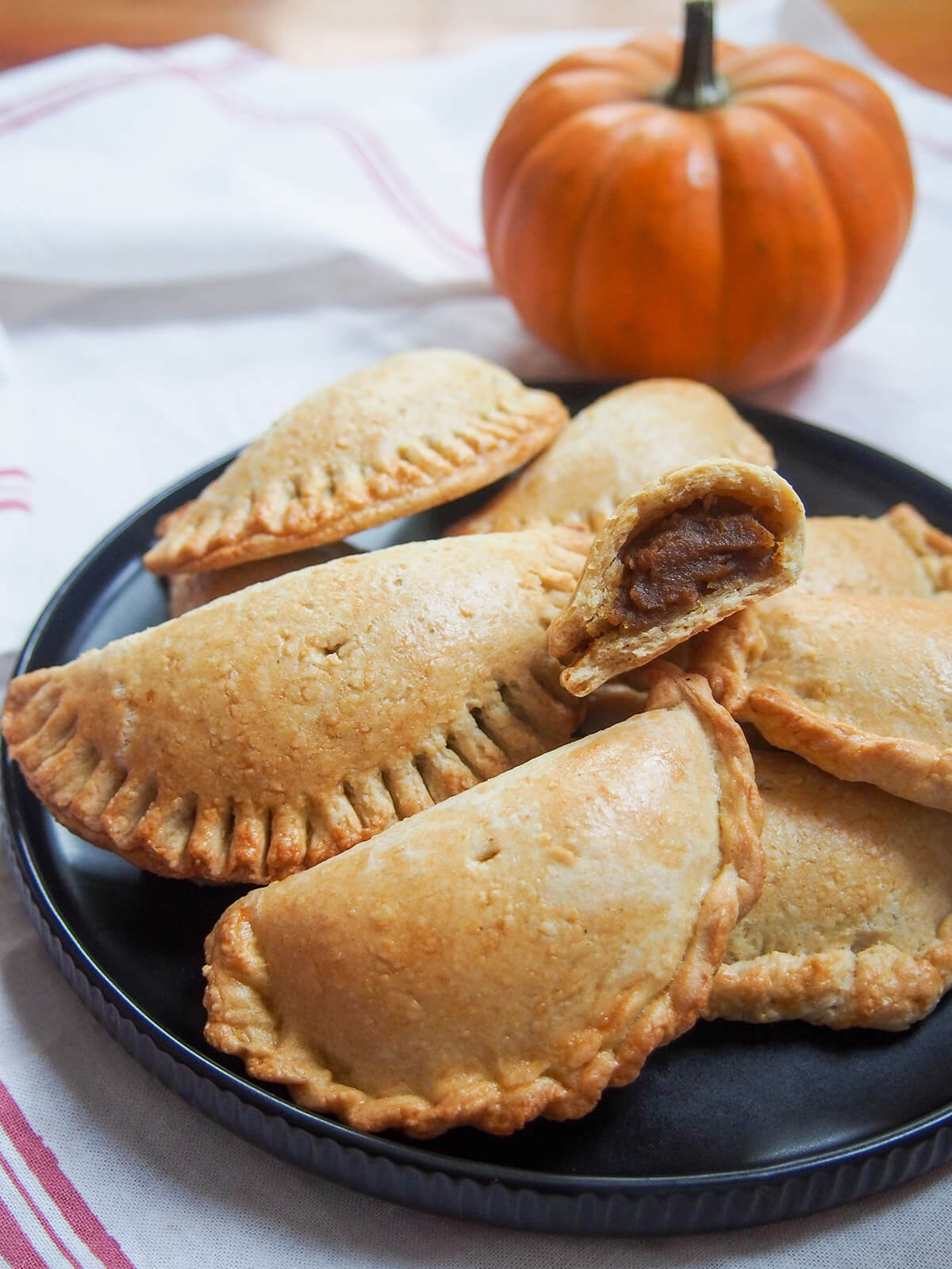 close view of part pumpkin empanada sitting on top of stack of more