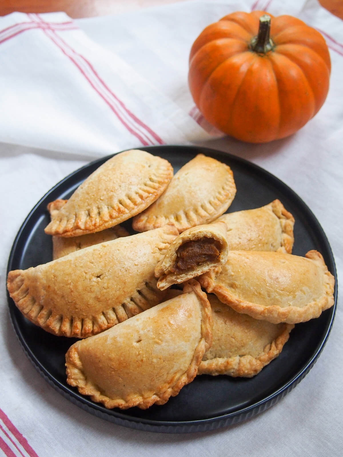 plate of pumpkin empanadas with mini pumpkin above plate