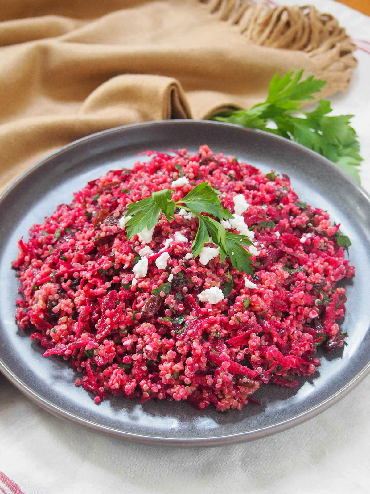 plate of raw beet quinoa salad with tan cloth behind
