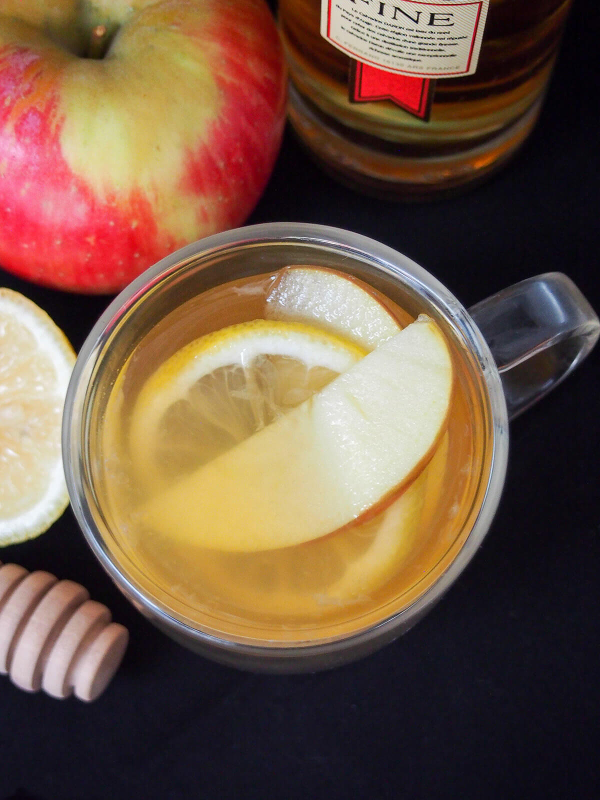 overhead view of glass of apple brandy hot toddy with apple and lemon slices in glass