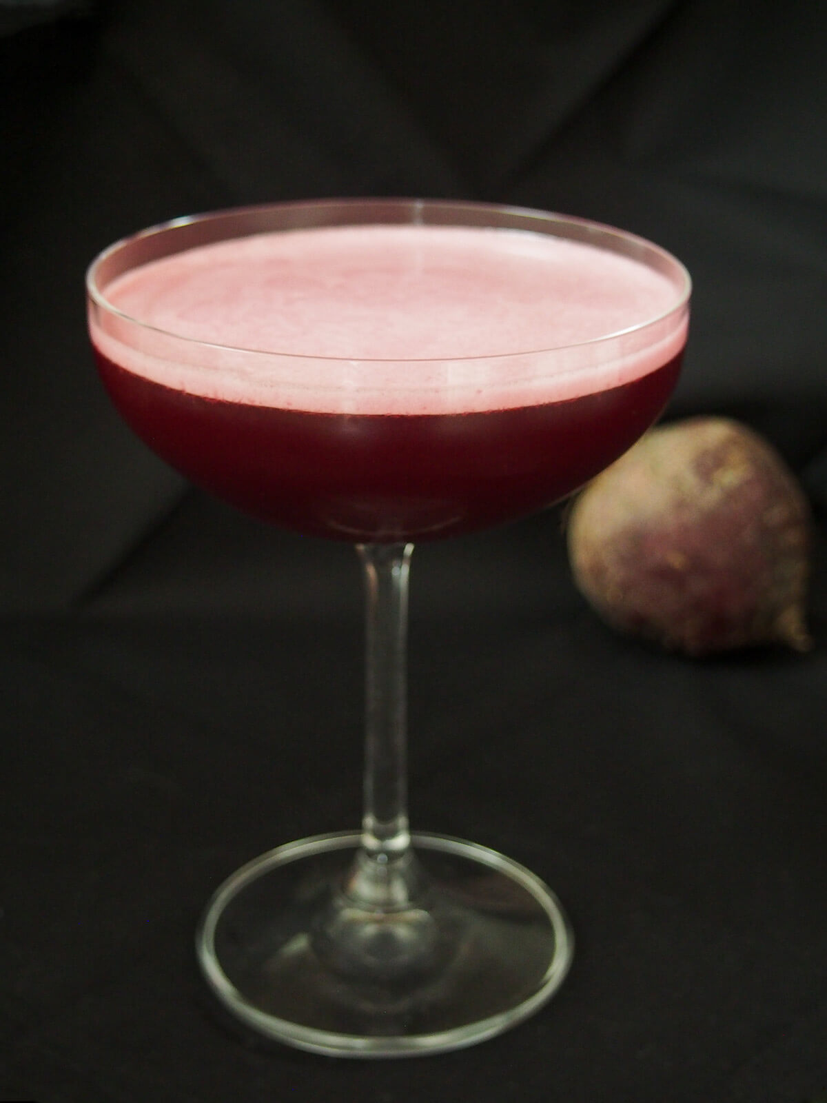 glass of beet negroni sour from the side showing foamed top