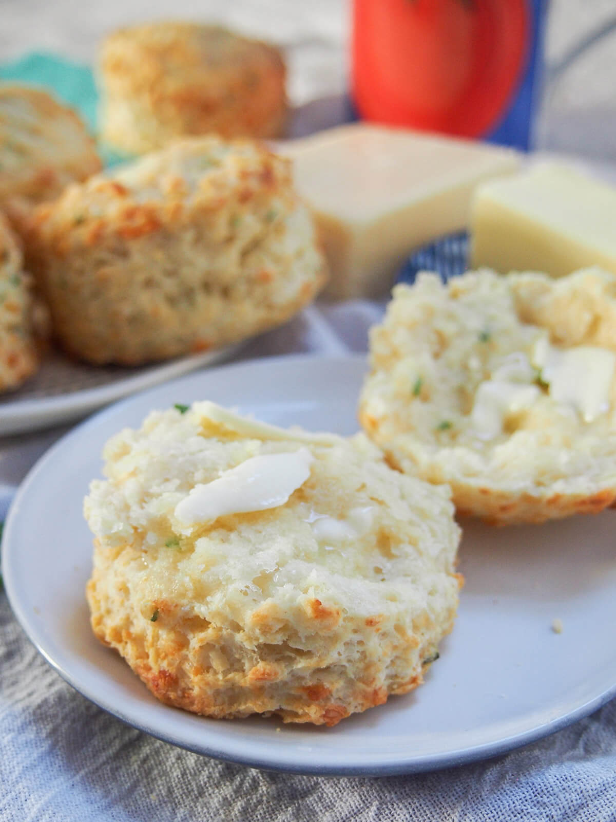 These savory cheese scones are easy to make, packed with cheese flavor yet surprisingly light. A delicious snack, side or base for a sandwich. split open cheese scone with butter on top