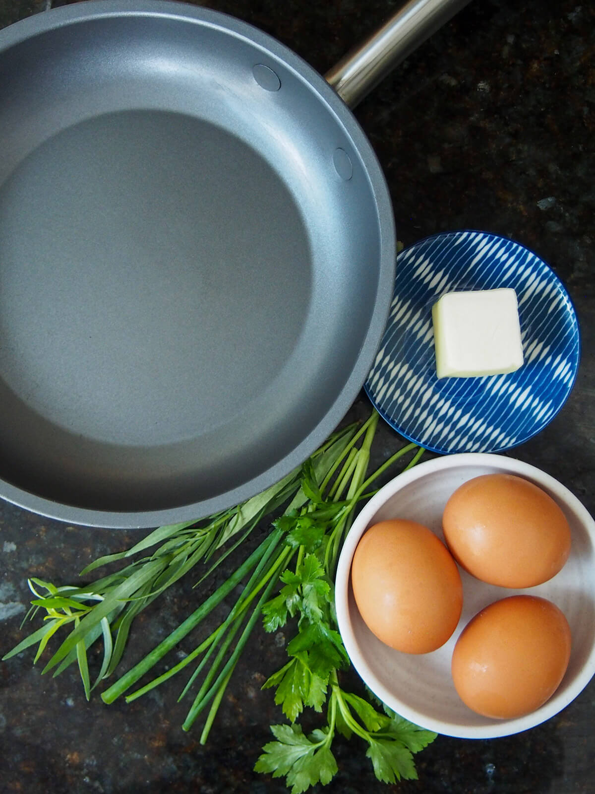 skillet to one side with butter, eggs and herbs to other