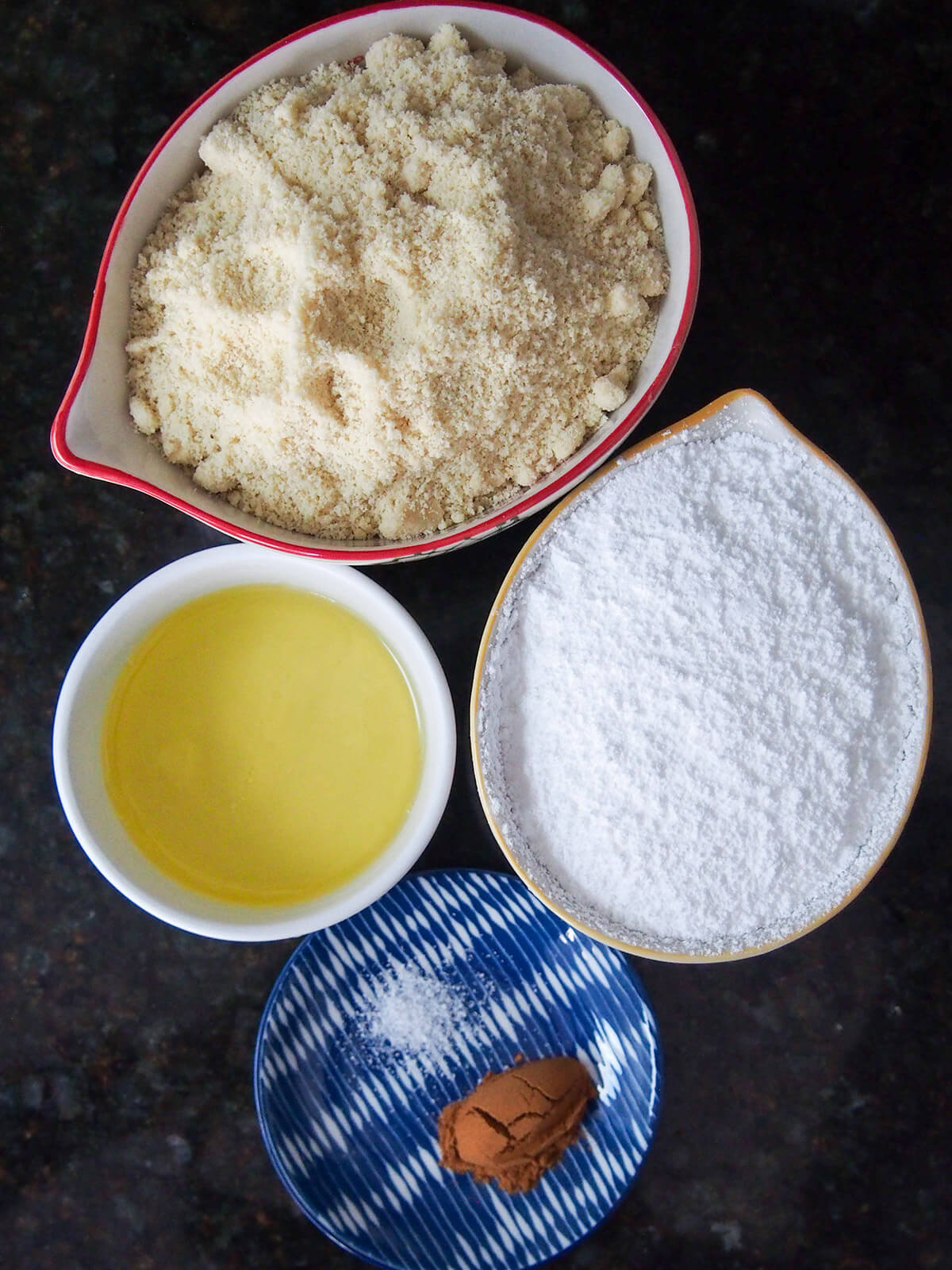 bowls of ground almonds powder sugar, egg white and cinnamon