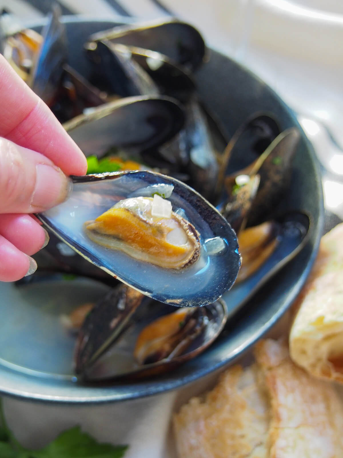 holding a mussel on the shell in hand over bowl